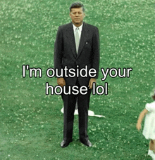 a man in a suit and tie is standing in a field with the words i 'm outside your house lol