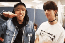 two young men are standing next to each other in a room and one of them is wearing a choker .