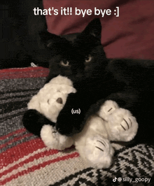 a black cat laying on a blanket holding a stuffed animal that says " that 's it bye bye "