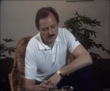 a man in a white shirt sits in a chair
