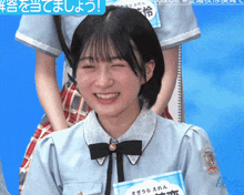 a girl wearing a blue shirt with a black bow and a name tag that says ' a ' on it