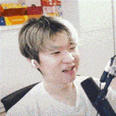 a young man is sitting in front of a microphone with his mouth open .