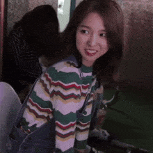 a girl in a striped shirt and overalls smiles for the camera