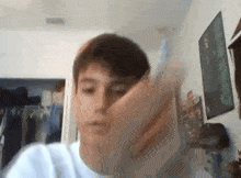 a young man is making a funny face while holding a cell phone in a room .