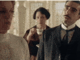 a man in a suit and tie stands in front of two women
