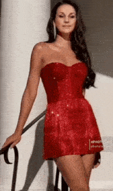 a woman in a red dress is leaning on a railing .