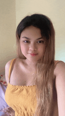 a woman in a yellow tank top is taking a picture of herself