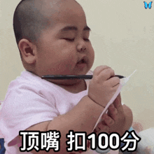 a baby is holding a pen and a piece of paper and says 100