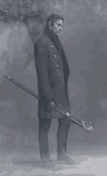 a man in a black coat is holding a long stick