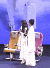 two women standing next to airplane seats that say cadt on them