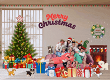 a group of people posing in front of a christmas tree with merry christmas written on the wall