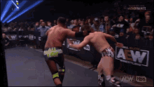 two men are wrestling in front of a crowd and a aew logo