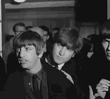 two men in suits and ties are standing next to each other in front of a crowd .