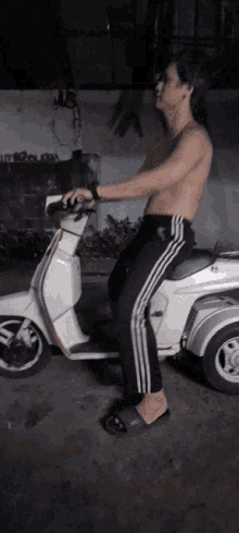a man without a shirt is riding a scooter