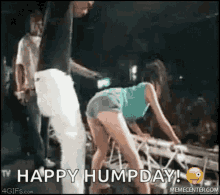 a man and a woman are dancing on a stage with the words happy hump day written on the bottom .