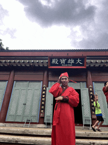 a man in a red outfit stands in front of a building that says great hall