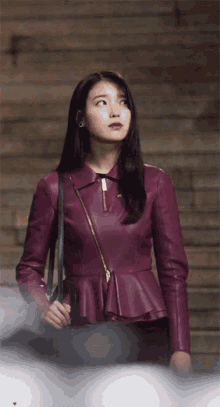 a woman in a purple leather jacket is standing on stairs