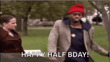 a man wearing a red hat is walking in a park with a woman .