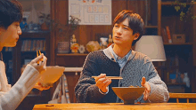 a man is sitting at a table with chopsticks and a bowl