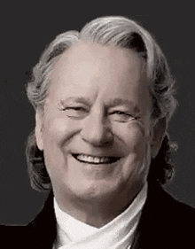 a black and white photo of a smiling man with gray hair .