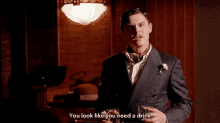 a man in a suit is holding a glass of whiskey and saying you look like you need a drink