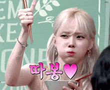 a woman holding chopsticks in front of a sign that says ' em ' on it