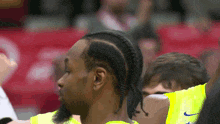 a man wearing a yellow nike jersey with braids on his hair
