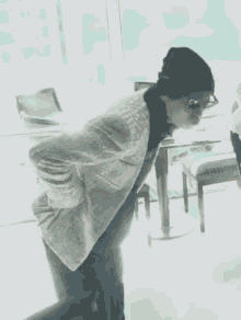 a woman wearing a beanie and glasses is standing in front of a table .