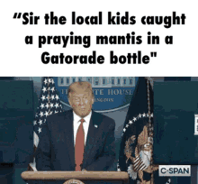 a man in a suit and tie stands at a podium with a gatorade bottle in front of him .