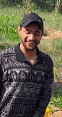 a man wearing a hat and a sweater is standing in a field .