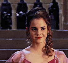 a woman in a pink dress is smiling in front of a staircase