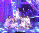a group of women dancing on a stage with purple lights behind them
