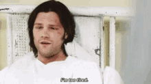 a man in a hospital gown is laying in a hospital bed .