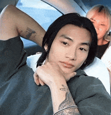 a man with a tattoo on his arm has his hand on his chin while a woman looks on