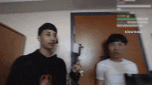 two men are standing next to each other in front of a door and the number 6304 is on the screen