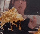 a woman is eating noodles with chopsticks in a restaurant .