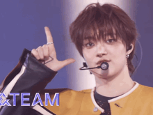 a young man wearing a microphone and a yellow jacket with the word team on the bottom right