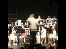 a man is standing in front of a large orchestra on a stage