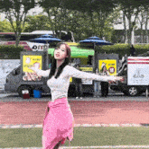 a woman in a pink sweater is standing in front of a food truck that says ' a ' on it