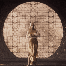 a woman standing in front of a circular window with a geometric pattern