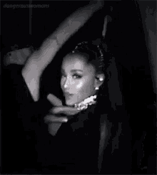 ariana grande is wearing a choker and a black dress in a black and white photo with a man behind her .