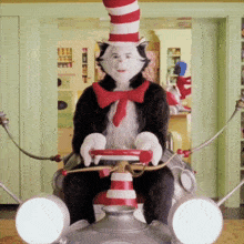 a cat in the hat is sitting on a chair with a steering wheel