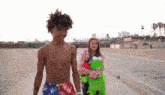 a shirtless man and a woman are walking down a sidewalk
