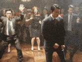 a group of people in suits and ties are dancing on a wooden floor
