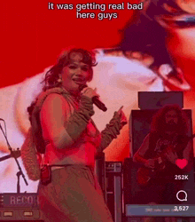 a woman is singing into a microphone on a stage in front of a large screen .