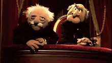 two muppets are sitting on a stage looking out the window