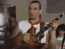 a man in a red tie is playing a guitar in front of a group of people .