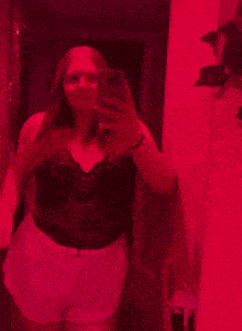 a woman is taking a picture of herself in a red room