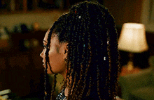 a woman with braids is wearing a sequined dress and earrings and looking at the camera .