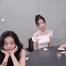 two women are sitting at a table with cards on it